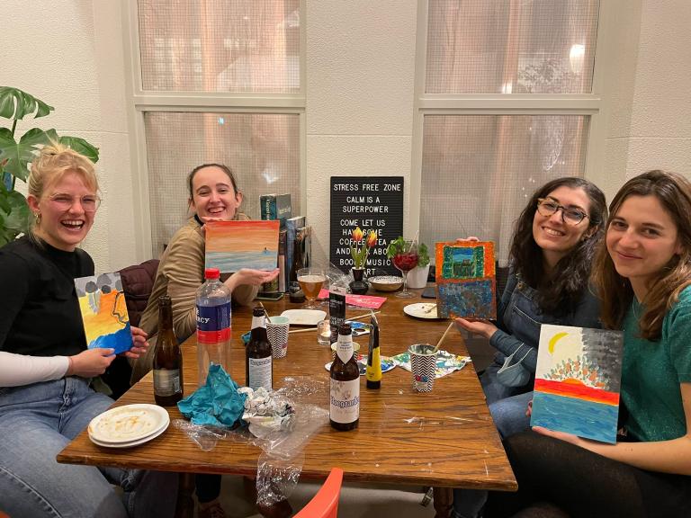 Students with painting canvases, sitting.